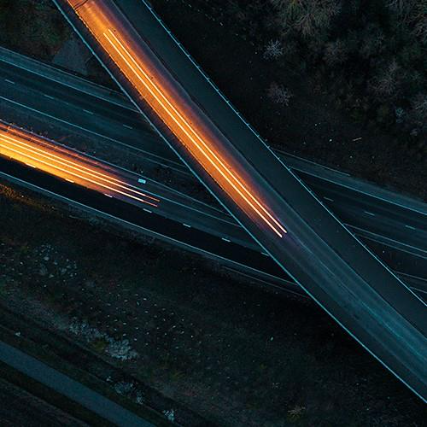 Abstract aerial view of intersecting roads at night with orange light trails from moving vehicles.