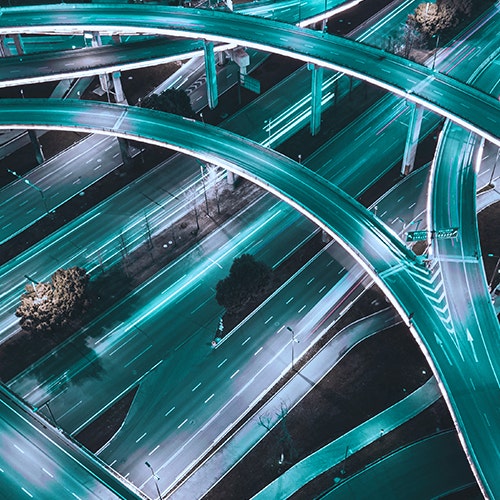 Aerial view of a multi-level highway interchange with light trails from moving traffic